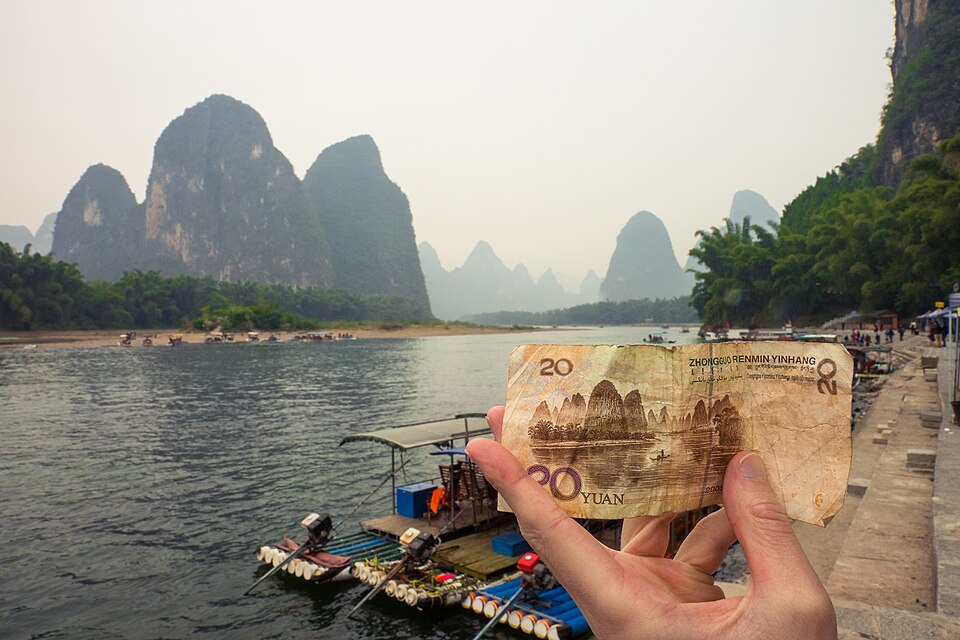 A 20-yuan banknote held against the Li River hills near Xingping